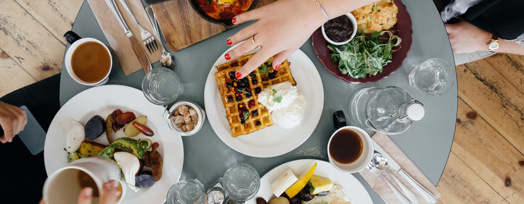 overhead shot of people having breakfast around a table of food and coffee